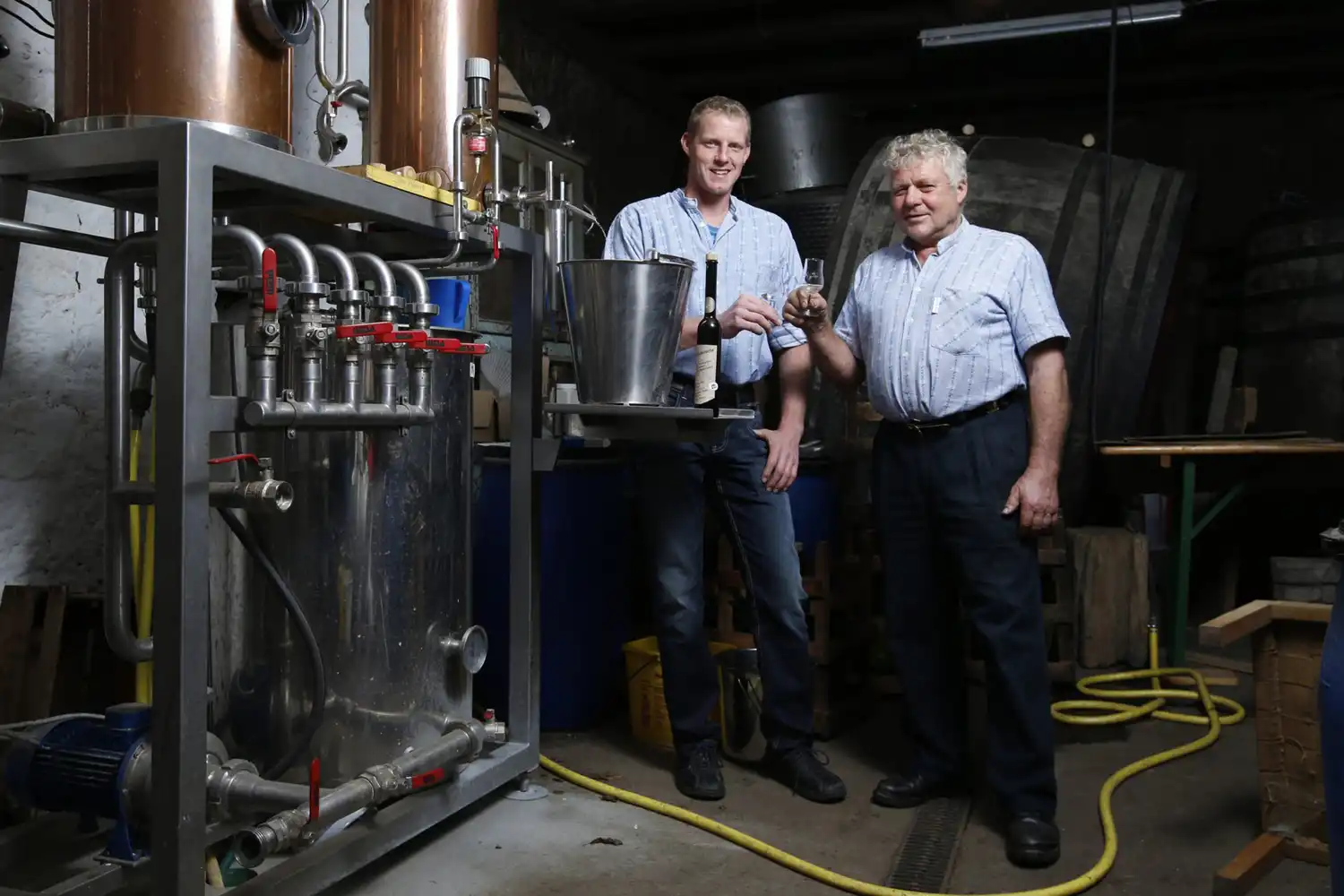 Hermann und Armin Röllin in ihrer Bauernhofbrennerei mit einem Glas Zuger Kirsch